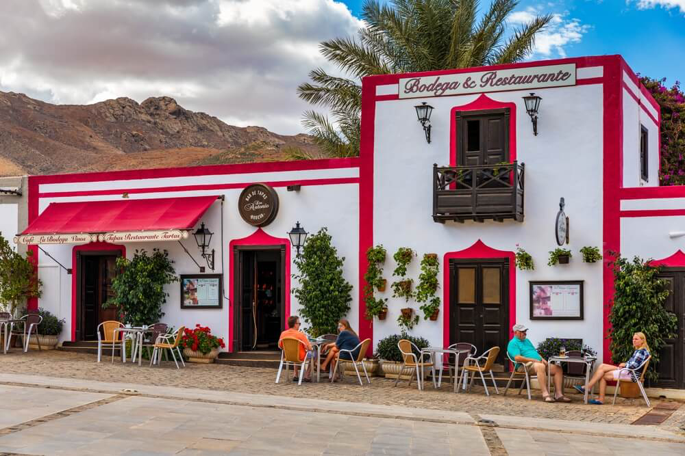 Couples sit outside a brightly painted restaurant in Fuerteventura