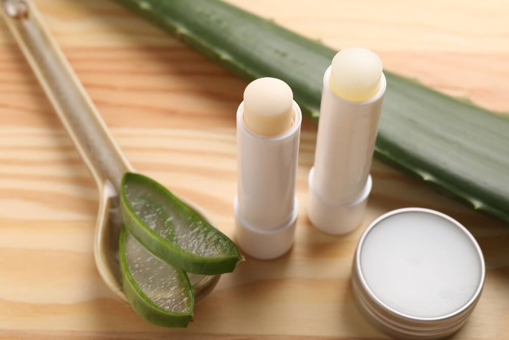 A close-up image of sliced aloe vera and aloe lip balm