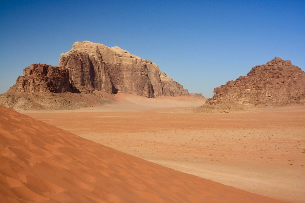 A sloping sand dune frames wind-worn desert rocks