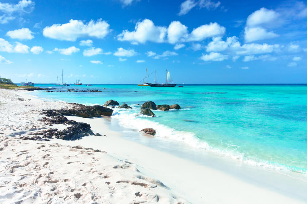 Arashi Beach auf Aruba mit Segelschiffen und Katamaranen vor der Küste.