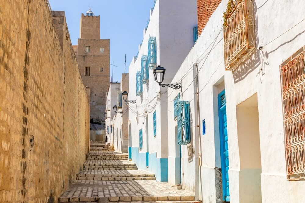 A quiet street leads up a hill of whitewashed houses and stone walls in Sousse medina