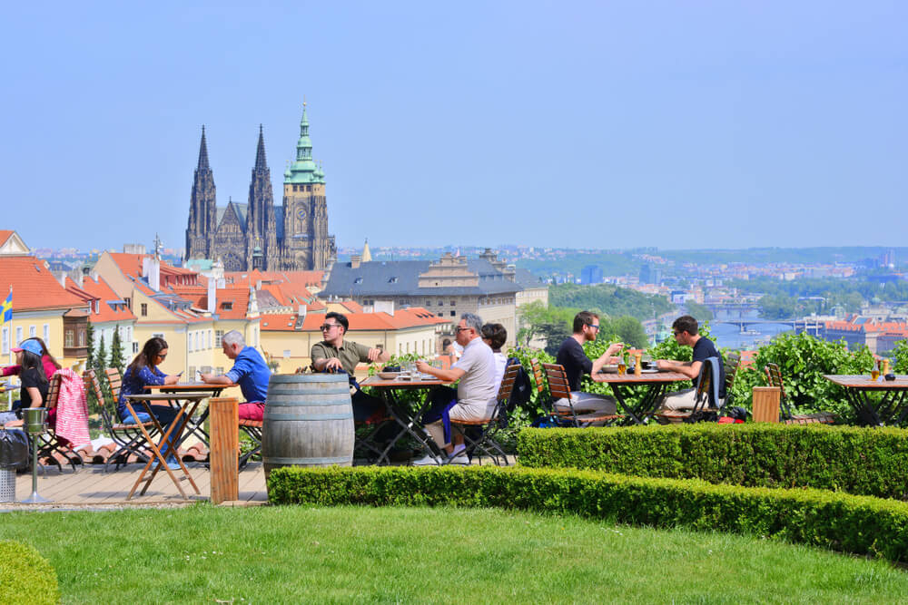 People drinking beer with a panoramic view of Prague behind