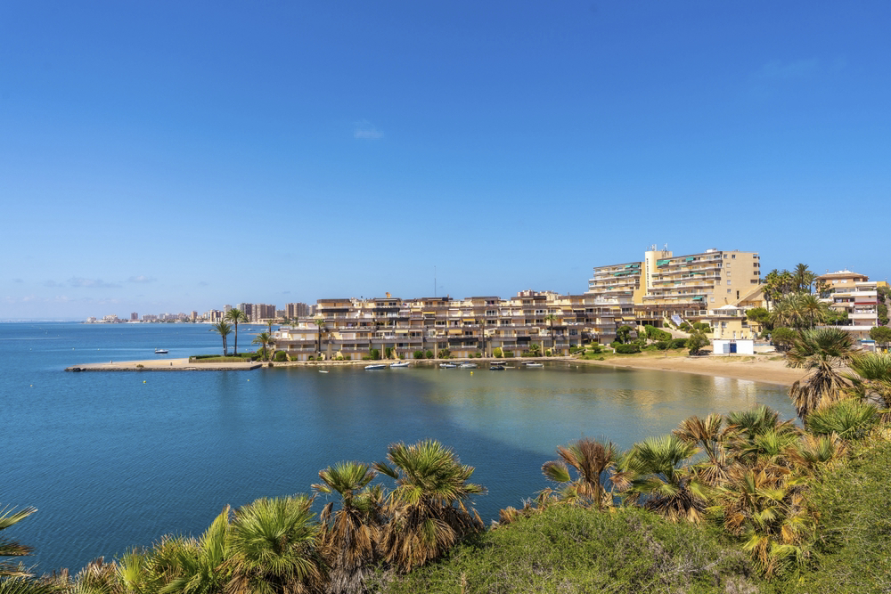 Best beaches in Murcia: a tranquil urban cove flanked by apartments and vegetation