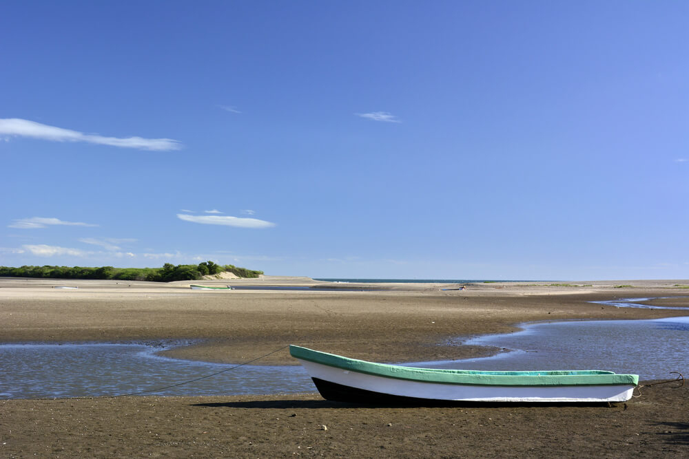 A small wooden boat sits on quiet las peñitas beach 