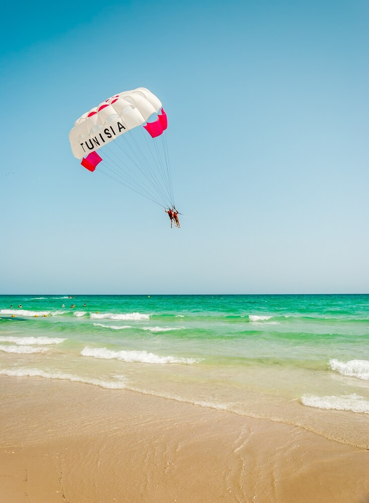 Tunisian beaches: Two people parasailing above an emerald sea in Tunisia