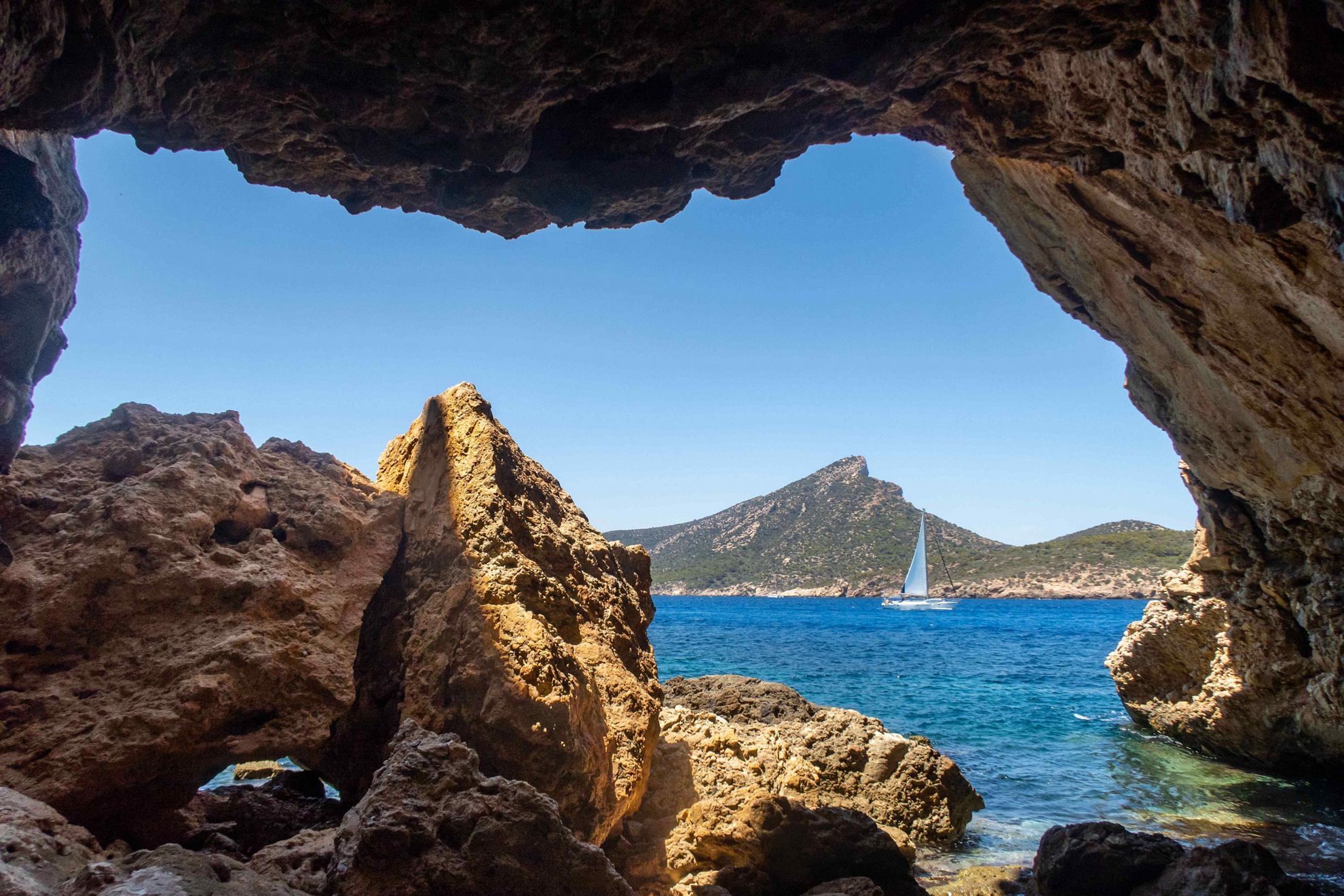 Dragonera Island: A view of a small rocky outcrop in the sea from a cave