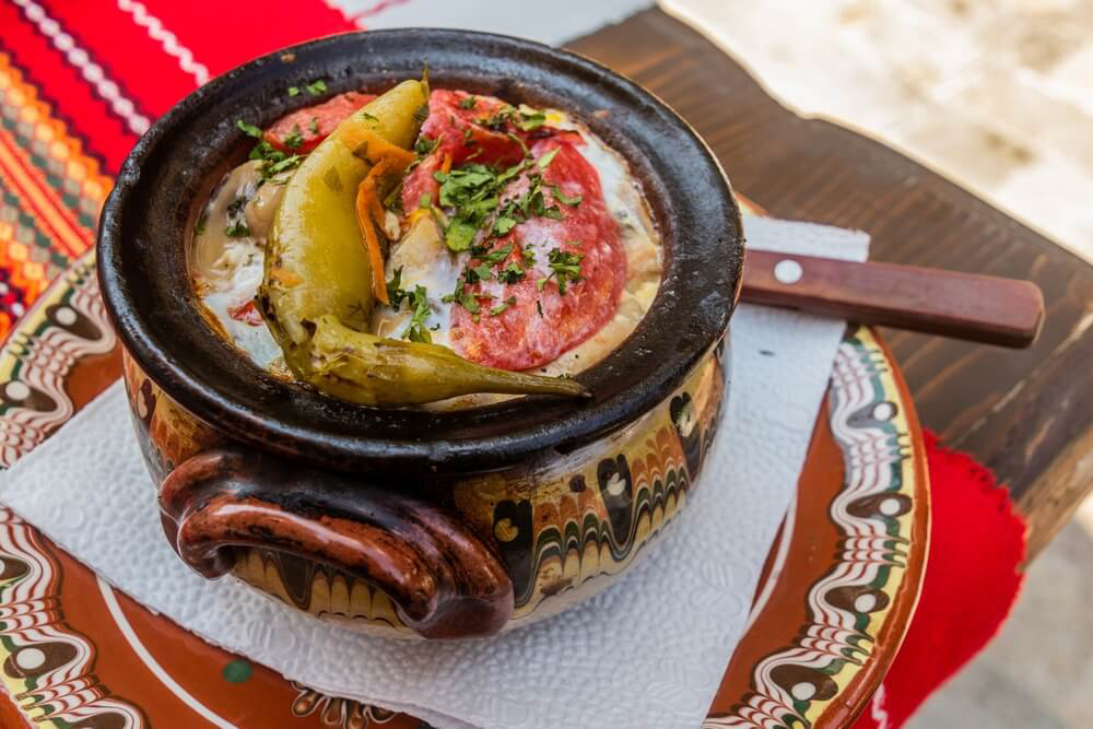 An earthenware bowl of Bulgarian stew garnished with a pepper