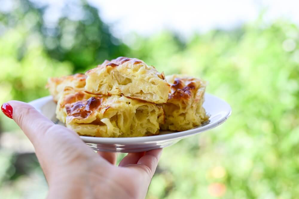 Bulgarian cuisine: a hand holds a plate of typical Bulgarian pastries