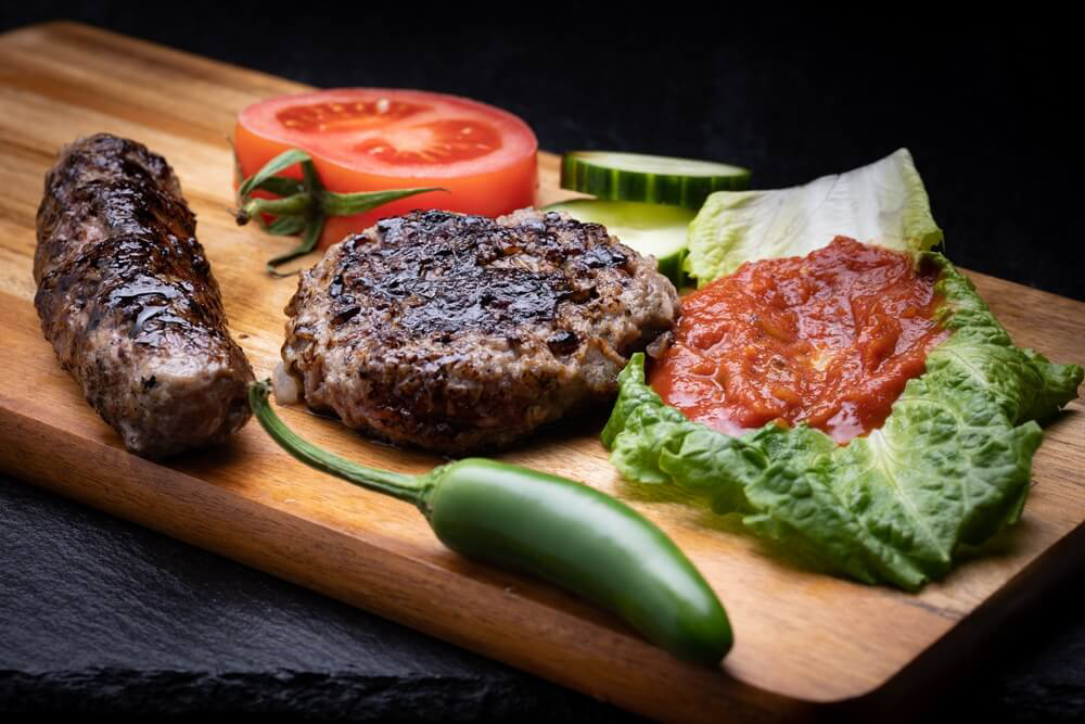 Bulgarian cuisine: grilled meat on a board accompanied by fresh vegetables and relish