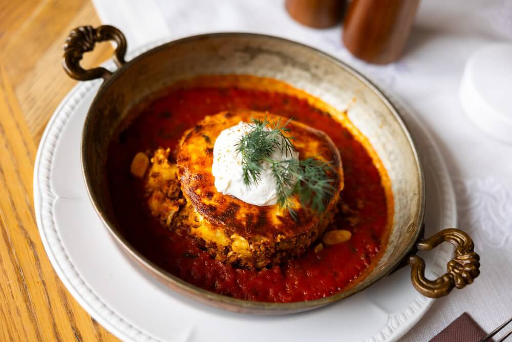 Close-up of a dish of Bulgarian moussaka topped with yoghurt dressing