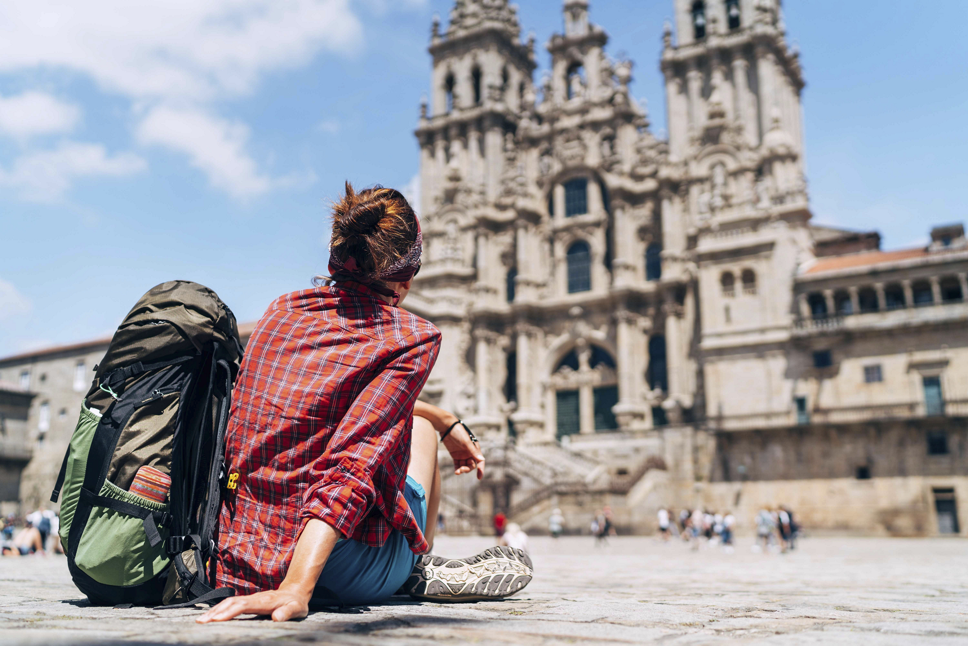 Camino de Santiago routes: a pilgrim sits before the Cathedral of Santiago de Compostela