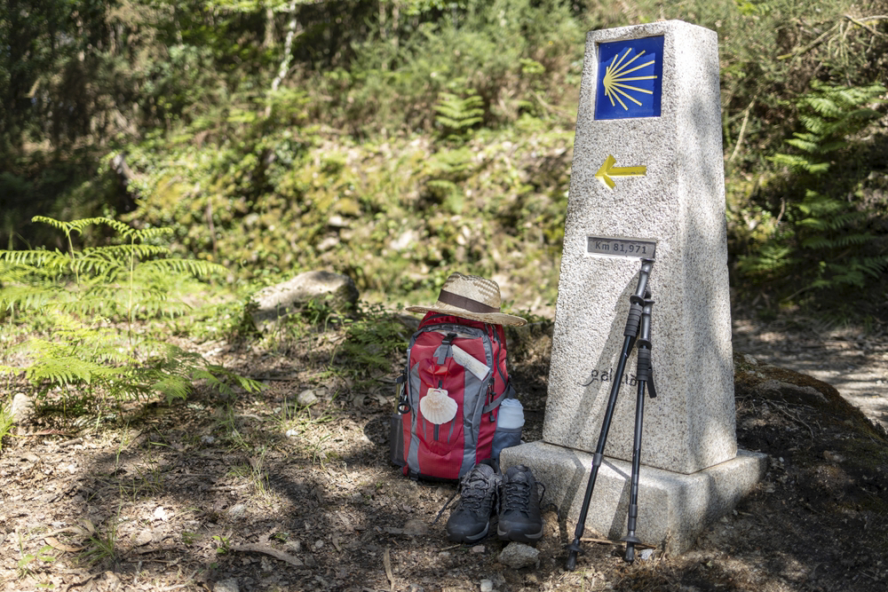 Camino de Santiago routes: hiker’s equipment leans against a Camino de Santiago waymark