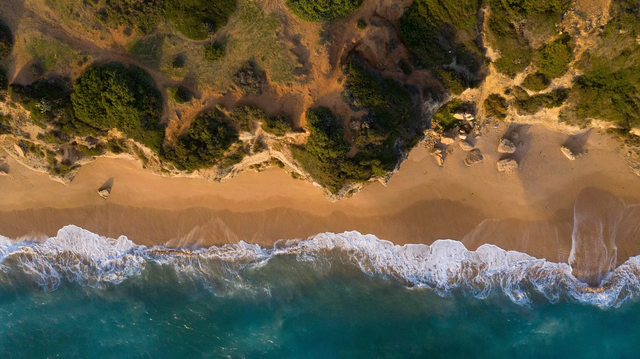 City breaks with beach: an aerial shot of a deserted beach backed by cliffs