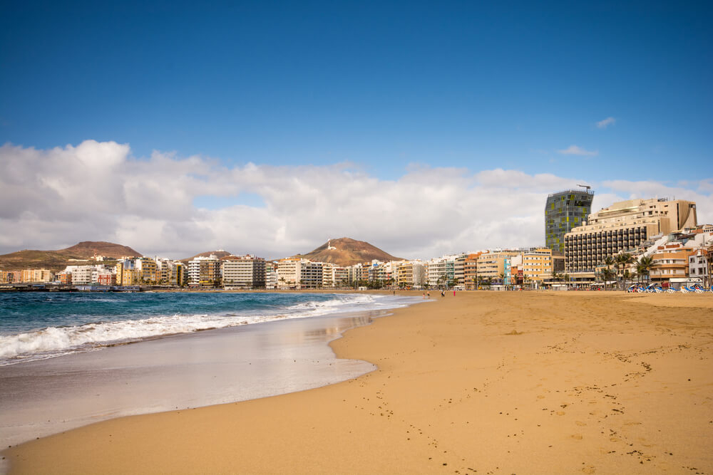 City breaks with beach: a wide sandy beach backed by apartments and hills