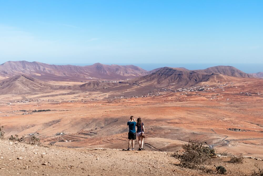 A couple contemplate the rugged volcanic landscape of Fuerteventura