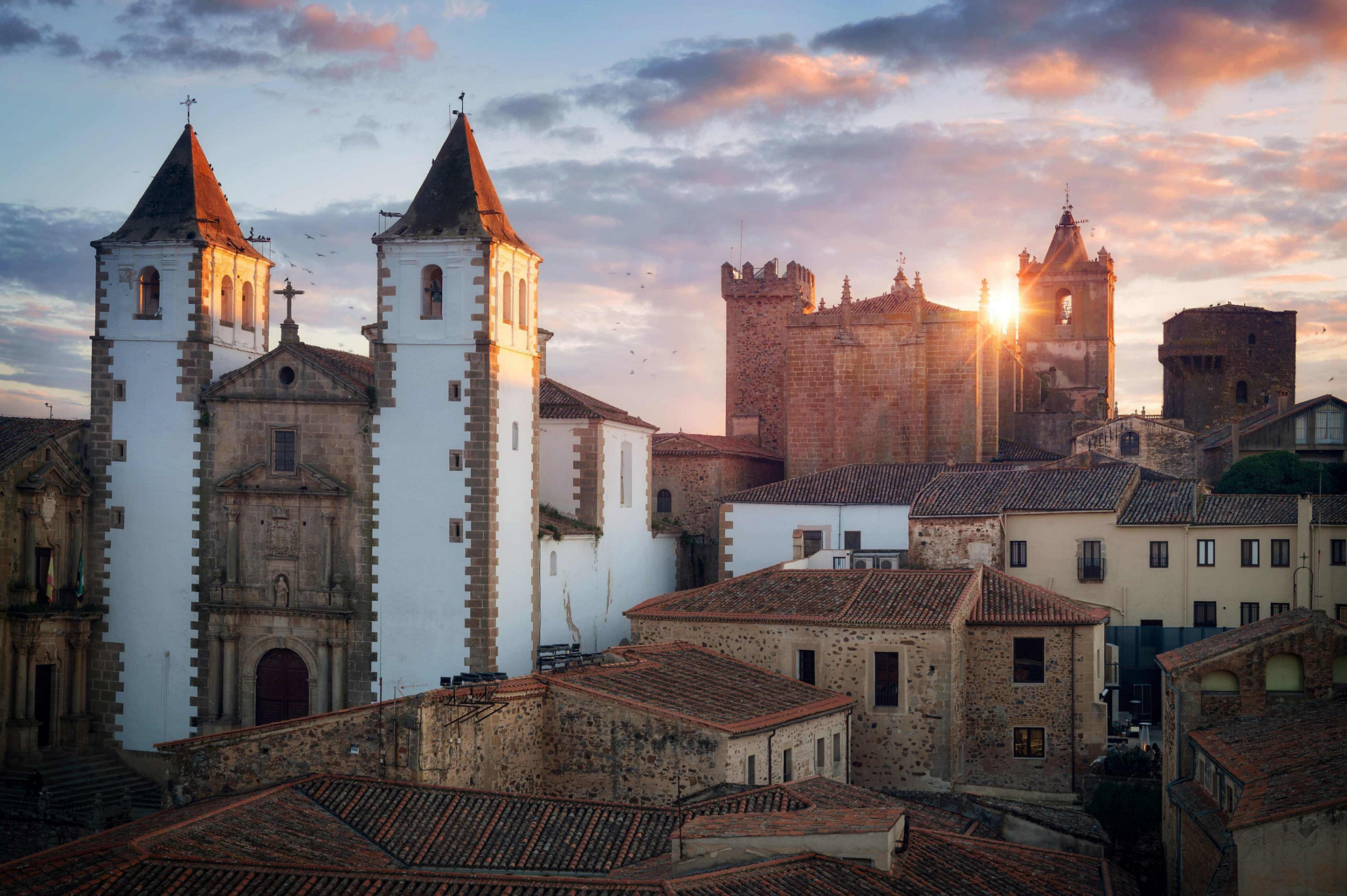 Cyber Monday hotel deals: late evening sun shines across terracotta roofs in Caceres old town