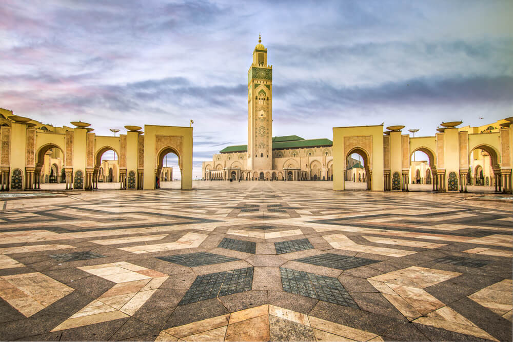 A wide marbled square decorated with arches leading to Hassan II Mosque in Casablanca