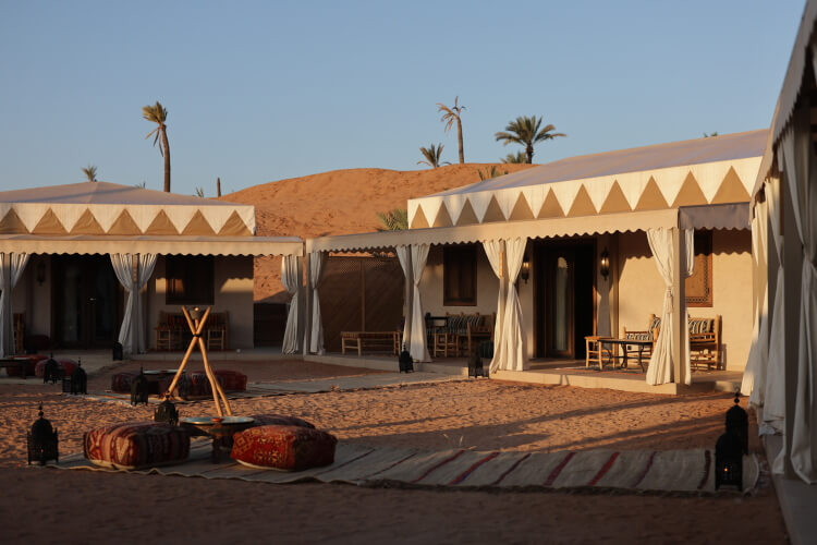 Desert safaris: luxury accommodation facing onto a communal area backed by dunes and palm trees