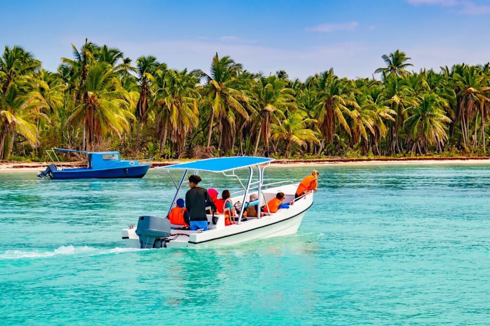 Ein Ausflugsboot vor einem palmengesäumten Strand auf Isla Saona, Dominikanische Republik