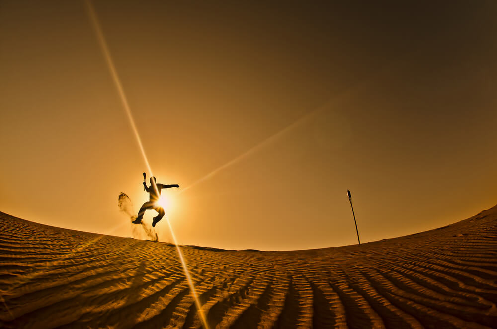 Dubai Aktivitäten: Sandsurfen bei Sonnenuntergang in der Wüste.