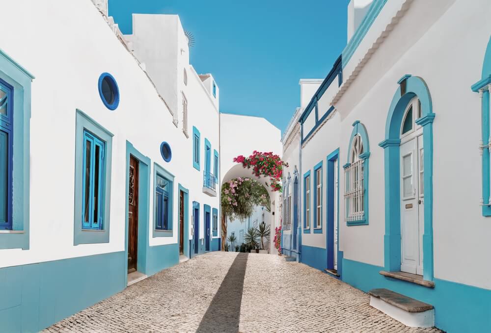 Gasse mit bläulich bemalten Häusern im Dorf Olhão bei Faro an der Algarve.