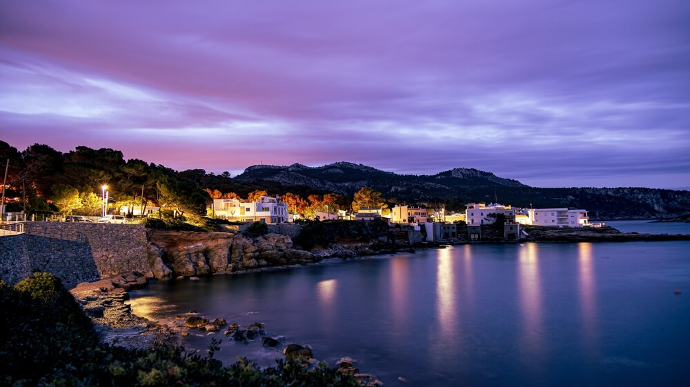 Illuminated houses overlooking the sea in Sant Elm in the half light