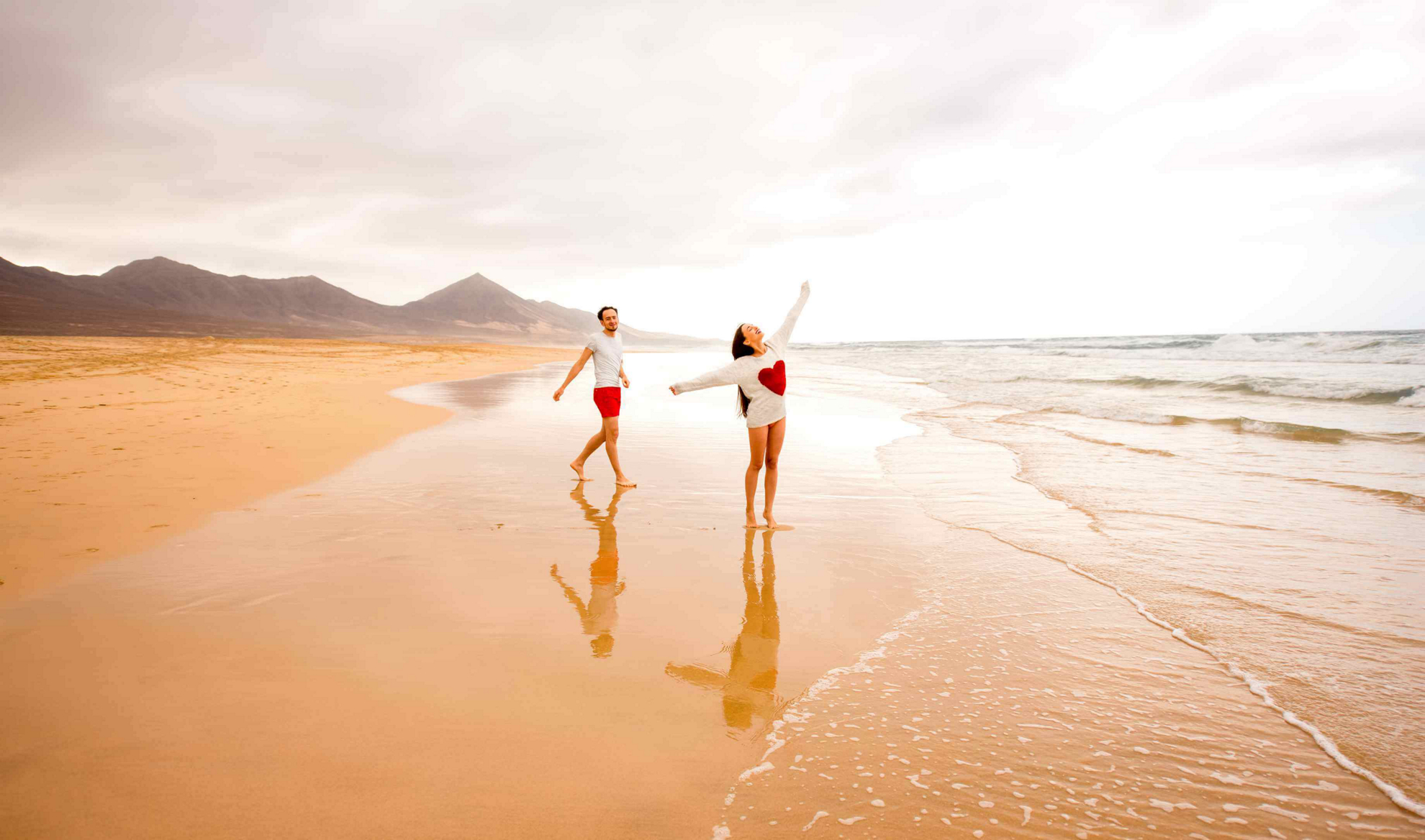 Fuerteventura for couples: a couple frolic on a deserted beach backed by volcanic hills  
