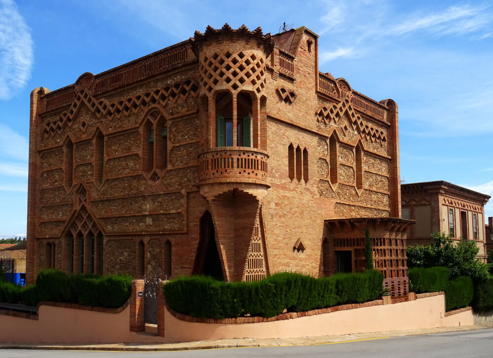 Colonia Güell: A golden stone building built in a Moorish style