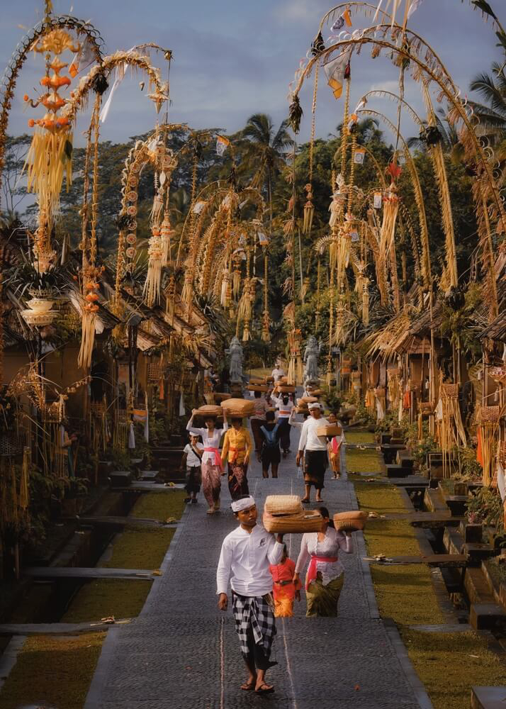 People walk a street lined with decorated bamboo poles during the Galungan festival