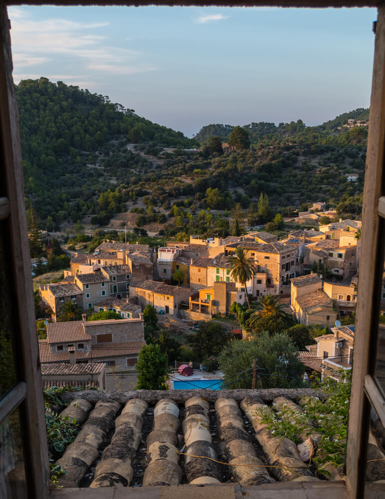 The stone houses of Estellencs and surrounding mountain greenery, seen from a window