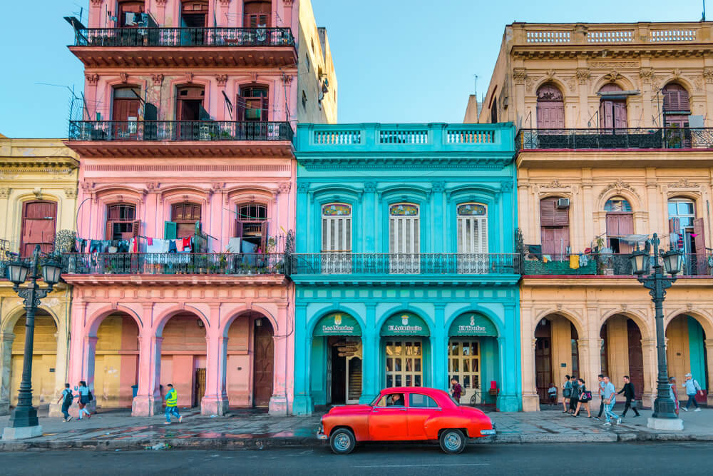 Places to visit in Cuba: A green vintage car driving in front of a state building in Havana
