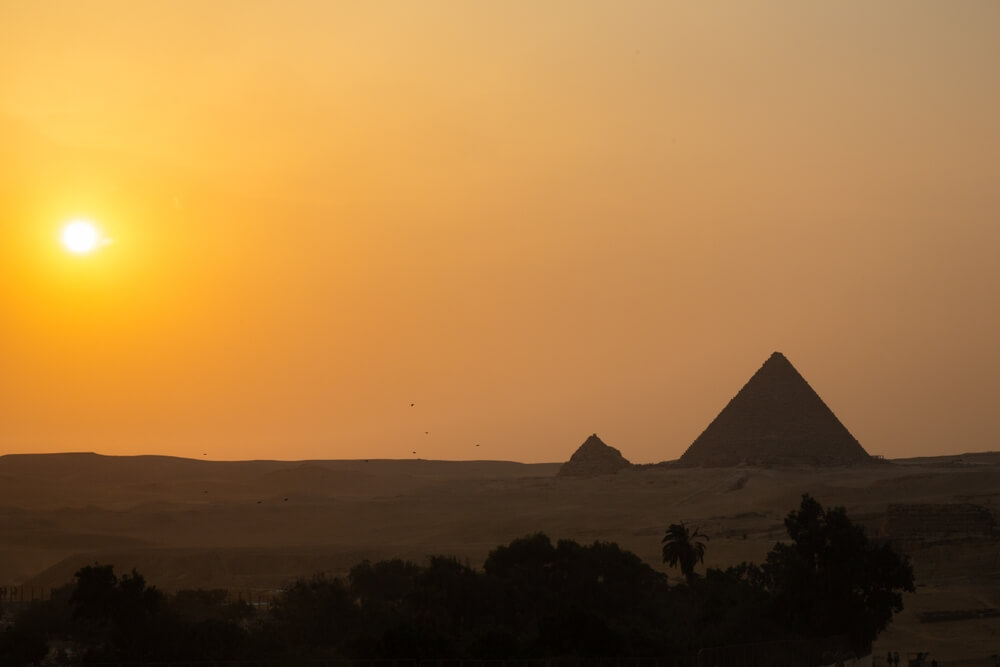 Sunset: A view of the pyramids with an orange sky behind them