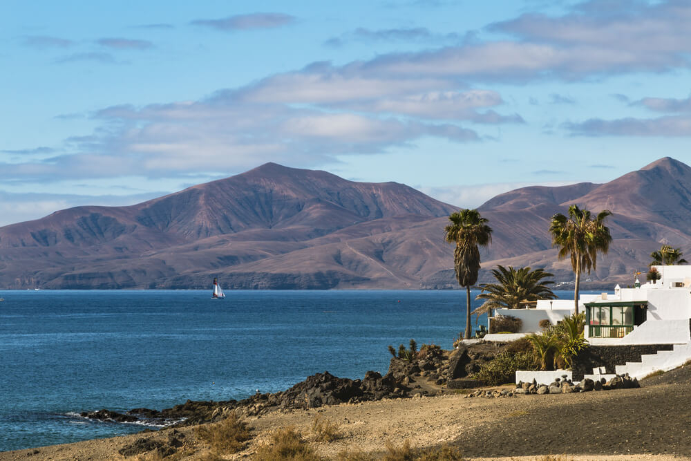 Blick übers Wasser auf eine vulkanische Landschaft bei Puerto del Carmen in Lanzarote