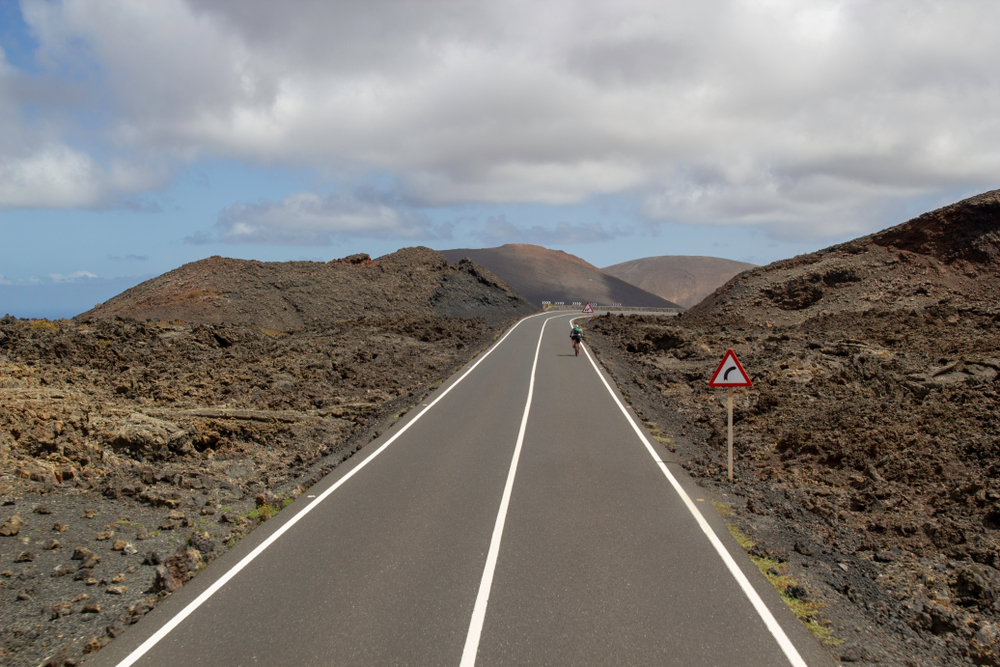 Radfahrer auf einer einsamen Bergstraße im Timanfaya-Naturpark auf Lanzarote