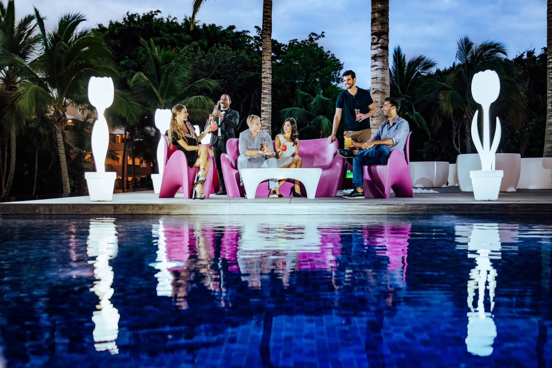 A group of friends enjoys a drink by the pool before an epic Riviera Maya nightlife experience