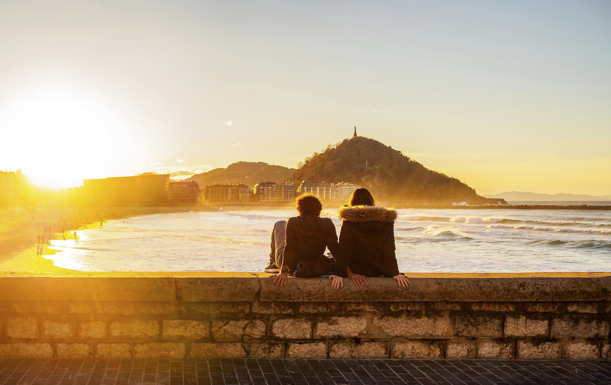 Ein Paar sitzt in der Abenddämmerung am Paseo Nuevo in San Sebastián.