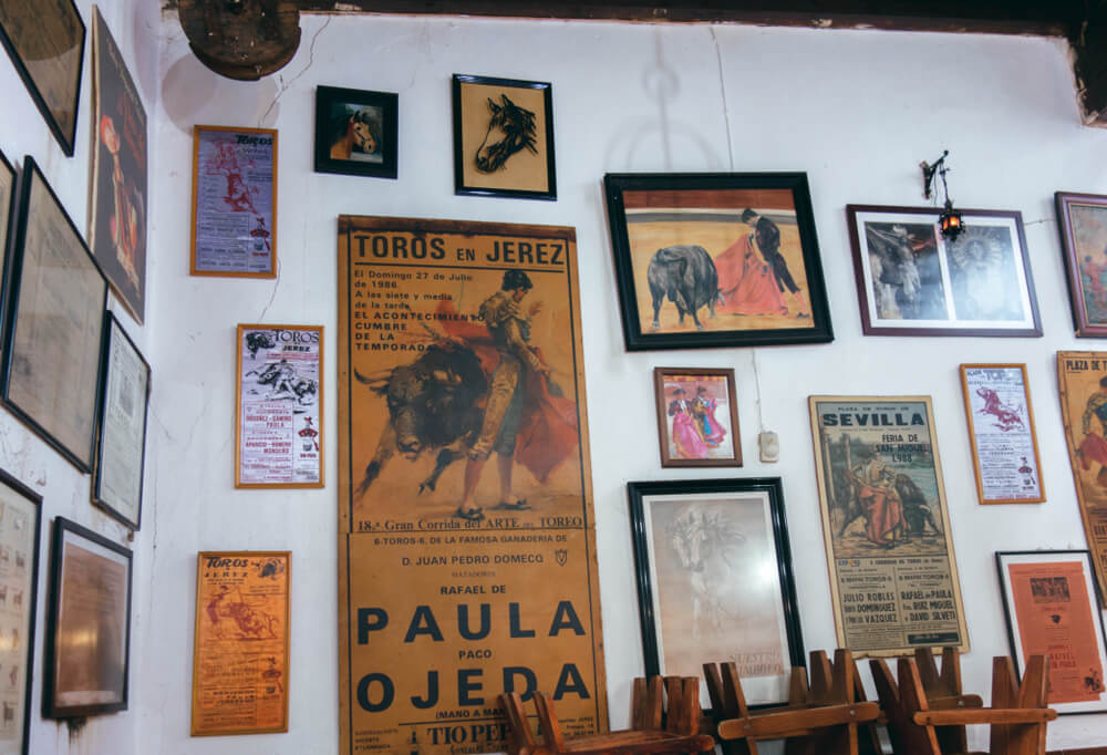Tabanco: A white wall with aged vintage Spanish cultural posters