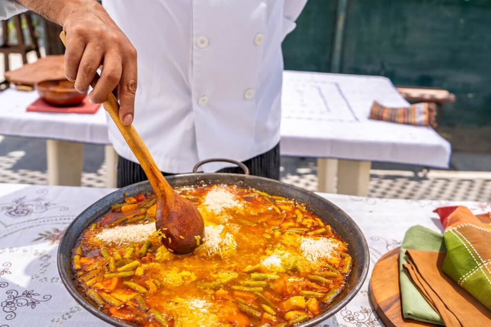 Spanische Küche: ein Koch bereitet eine valencianische Paella zu