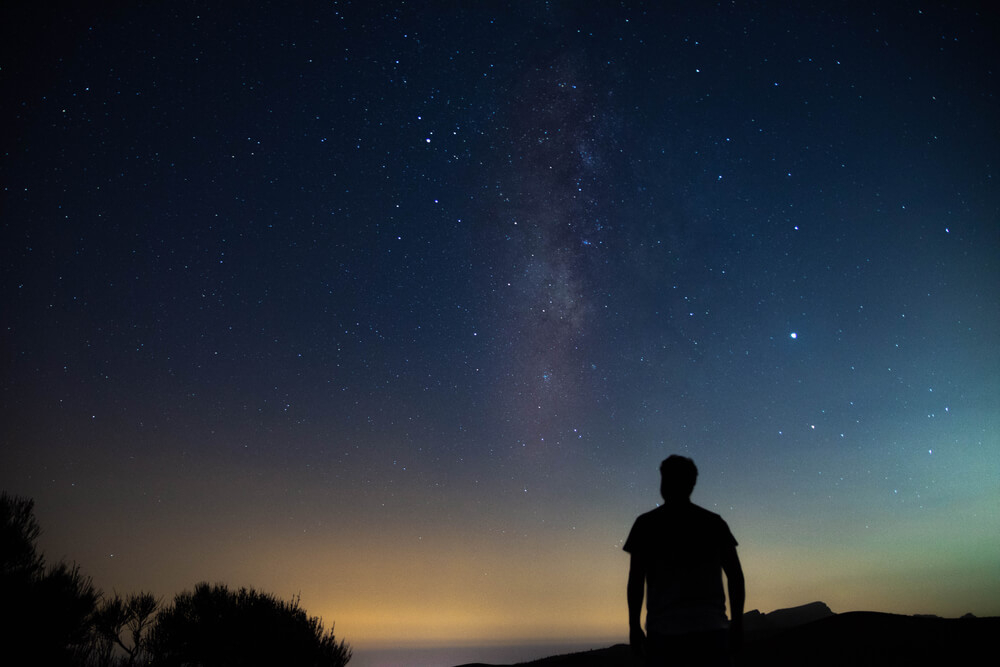 Ein Wanderer betrachtet den nächtlichen Sternenhimmel
