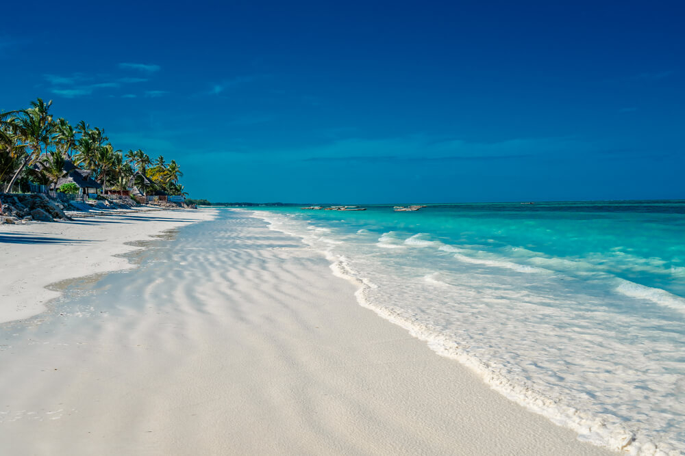 Jambiani Beach: a white sand beach lined with palm trees with turquoise waters and fishing boats