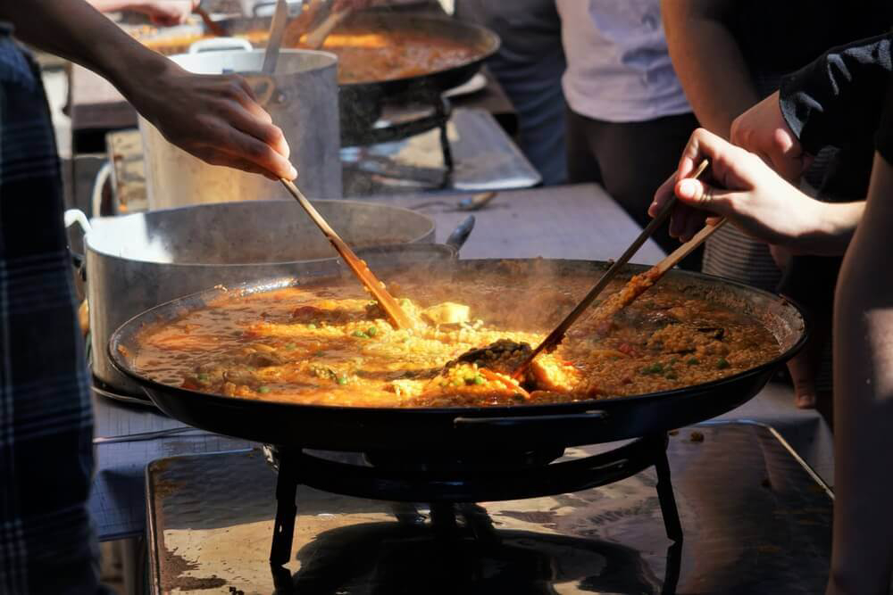 Köche bereiten eine authentische valencianische Paella zu.