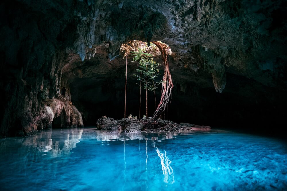 Weihnachten in Mexiko: türkisblaue Cenote in einer Höhle mit Lichteinfall durch eine Öffnung