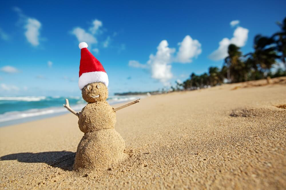 Weihnachten in der Karibik: Schneemann aus Sand mit Weihnachtsmütze am Strand