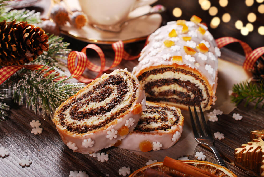 Der polnische Weihnachtskuchen Makowiek aufgeschnitten auf einem festlichen Tisch.