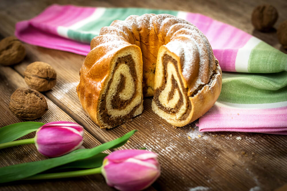Die slowenische Weihnachtsspezialität Potica auf einem Tisch mit Tulpen.