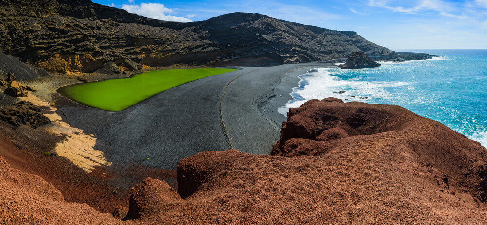 A black volcanic beach framed by dark, rugged hills in Lanzarote