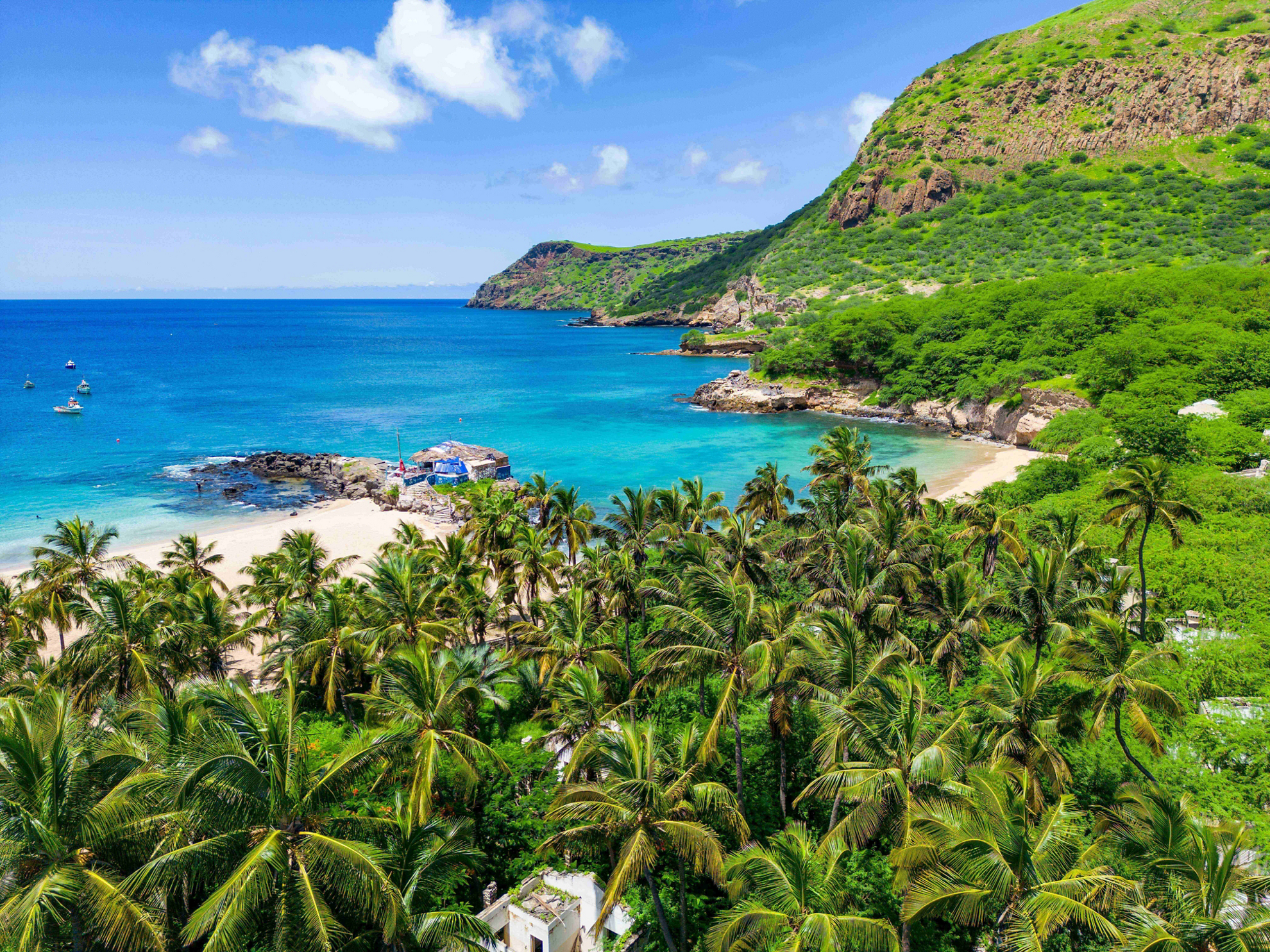 World Tourism Day: a tropical beach framed by palm trees and green cliffs in Cape Verde