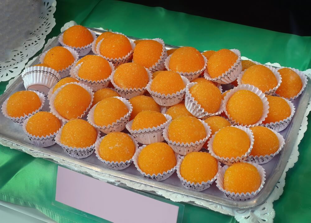Yemas: Yellow sweets in red paper cups on a blue surface