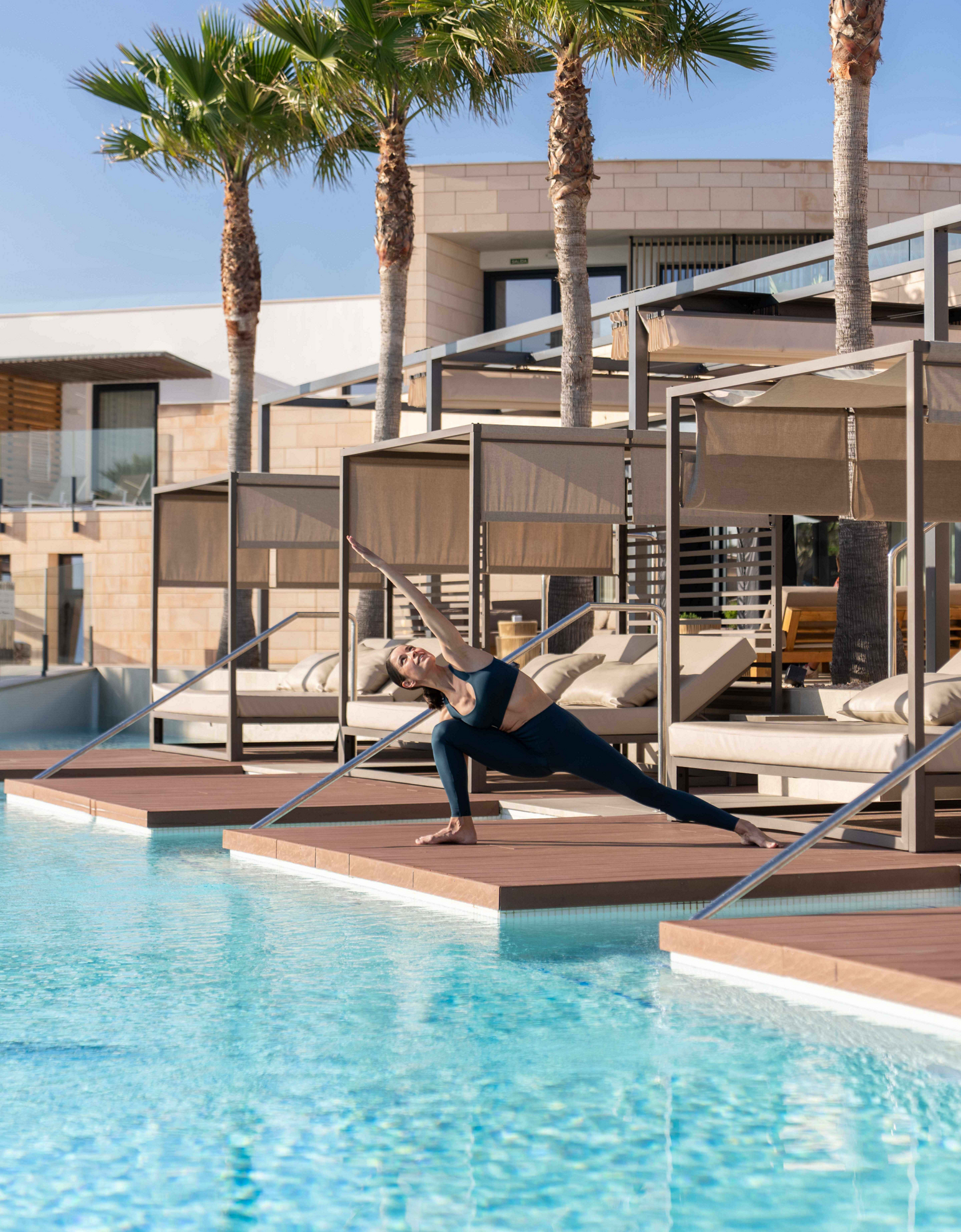 A woman practices poolside during her yoga vacation.