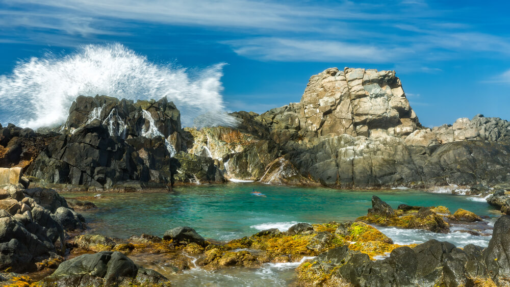 Conchi Natural Pool in Arikok National Park, surrounded by rugged rocks and crashing waves.